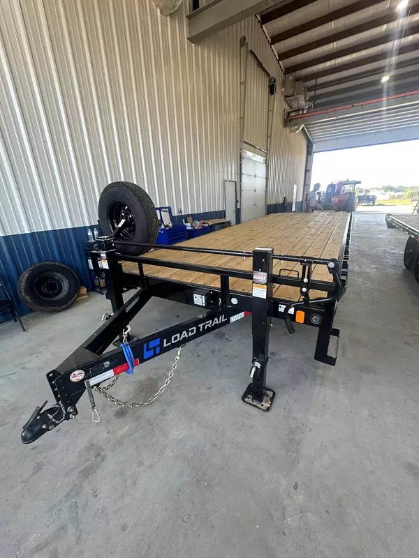 A black Load Trail deckover trailer inside a workshop